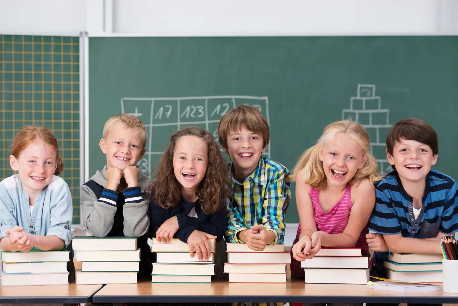 lachende kinder stützen sich auf schulbücher